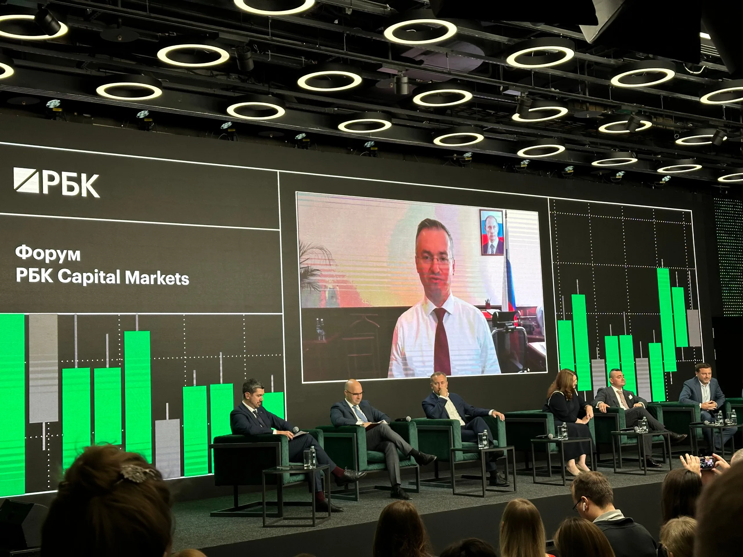 На сцене форума РБК Capital Markets идёт дискуссия; один из выступающих подключён по видеосвязи